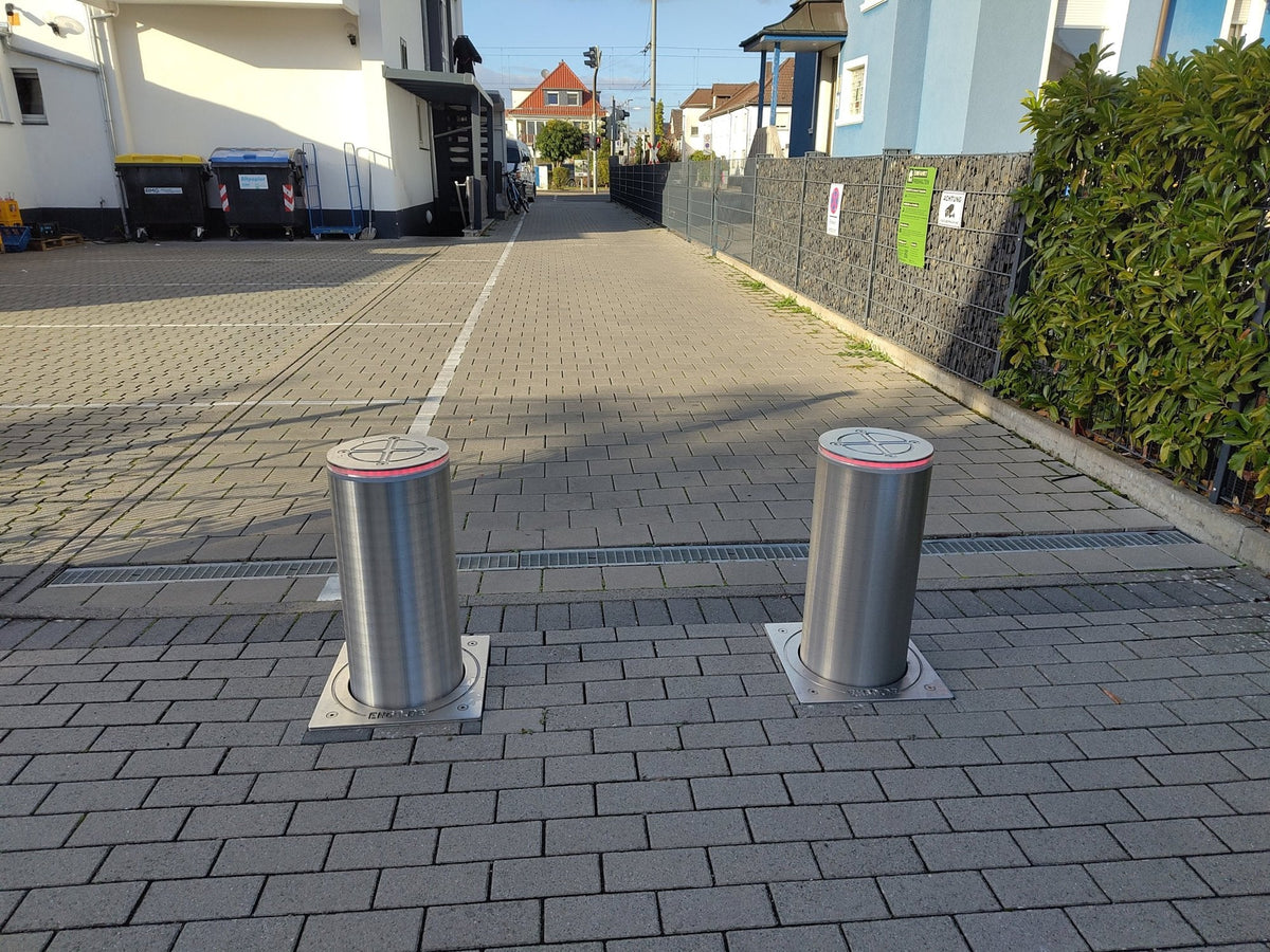 Zwei ausgefahrene versenkbare Edelstahl-Poller sperren die Durchfahrt einer gepflasterten Privatzufahrt