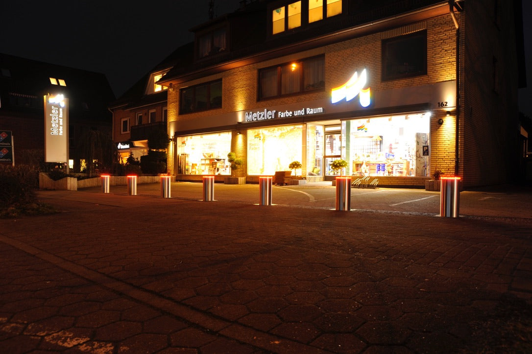 Versenkbare Poller mit LED-Beleuchtung bei Nacht vor einem Ladengeschäft – Braun Antriebe