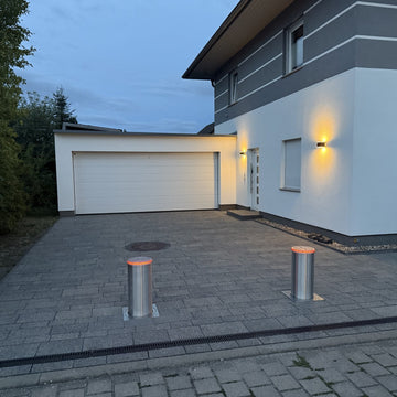 Versenkbare Edelstahl-Poller mit rotem LED-Leuchtring bei Nacht vor Einfahrt