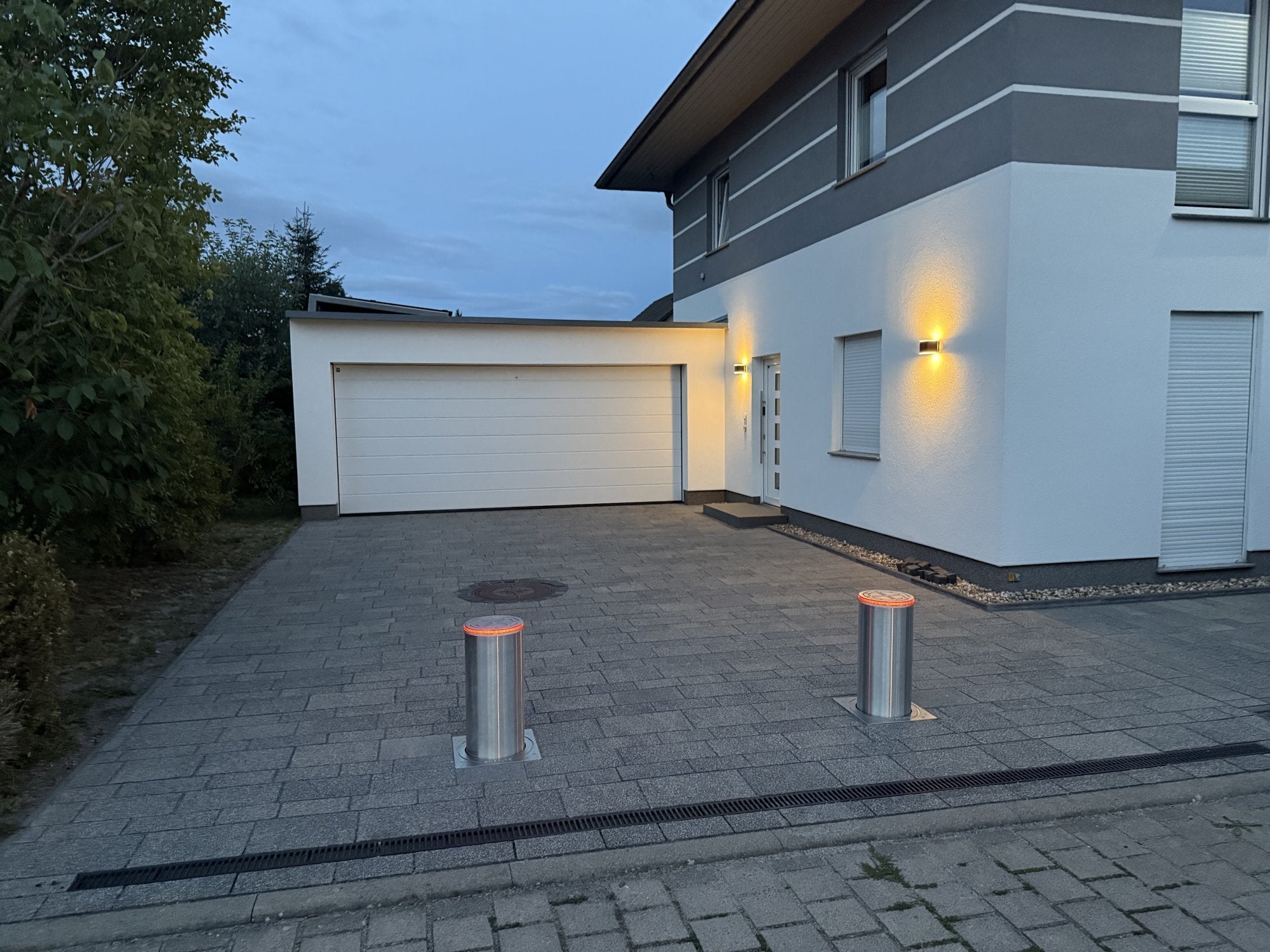 Versenkbare Edelstahl-Poller mit rotem LED-Leuchtring bei Nacht vor Einfahrt
