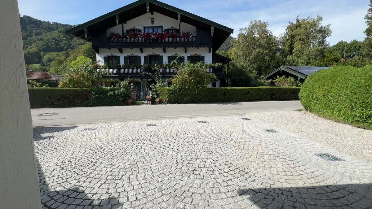 Versenkte Edelstahl-Poller V4A: Nur die bündigen Deckel liegen im Granit-Kleinpflaster einer Hofeinfahrt in Oberbayern