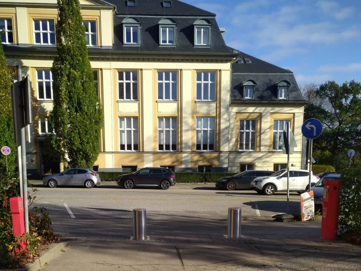 Zwei versenkbare Edelstahl-Poller sichern die Durchfahrt zu einem Universitäts-Parkplatz