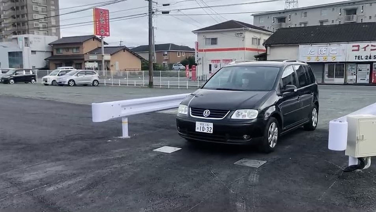Versenkbare Poller von Braun Antriebe auf einem Parkplatz in Japan: Ein Auto fährt über die abgesenkten Poller, rechts der Technikschrank